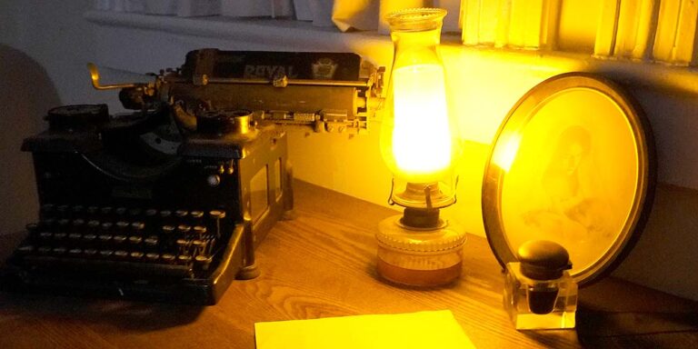 desk at the Old Jail featuring a typewriter, lamp and portrait at night